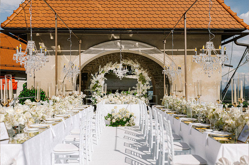 Bespoke ceremony design for a 2025 Lake Bled wedding at Bled Castle with chandeliers and white floral styling