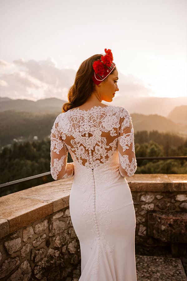 A back view of an amazing bride in a lace wedding dress on a beautiful bled castle terrace.
