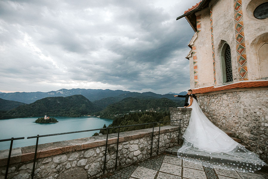 Groom is showing to the Bride Bled town from Lake Bled Casle terrace next to Bled Chapel.