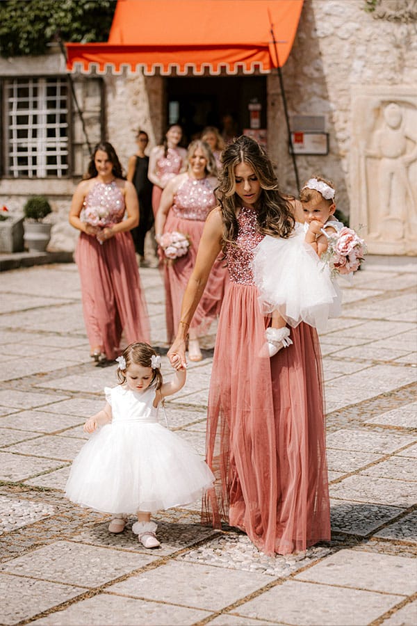 Bridal entrance at Bled Castle with bridesmaids and their young kids with small bouquet.