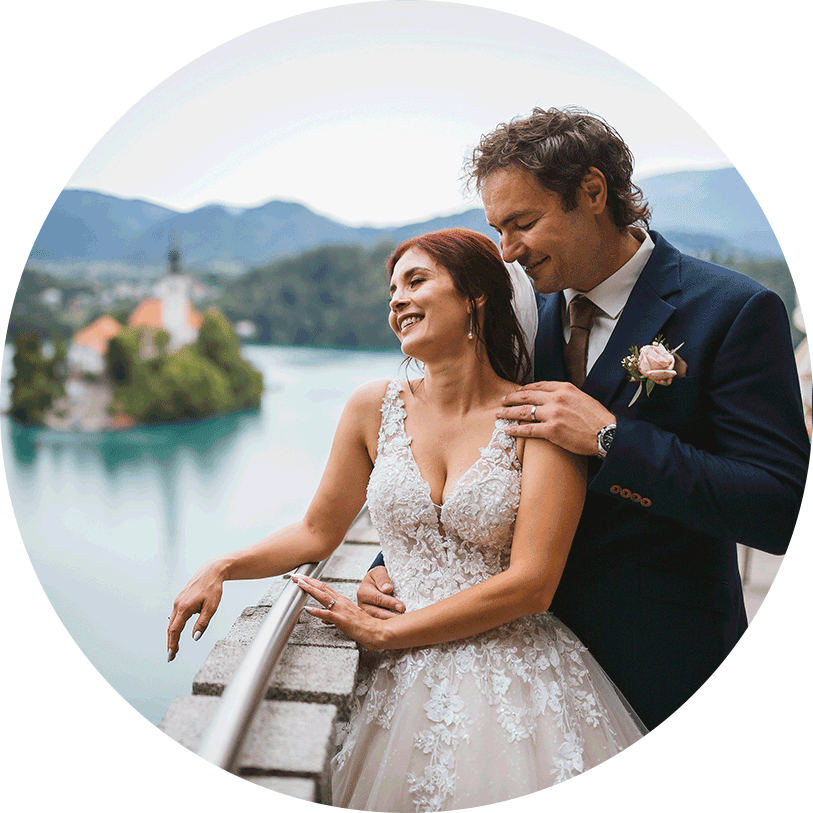 Happy wedding couple hugging on the Vila Bled bridge and looking the beauty of lake Bled.
