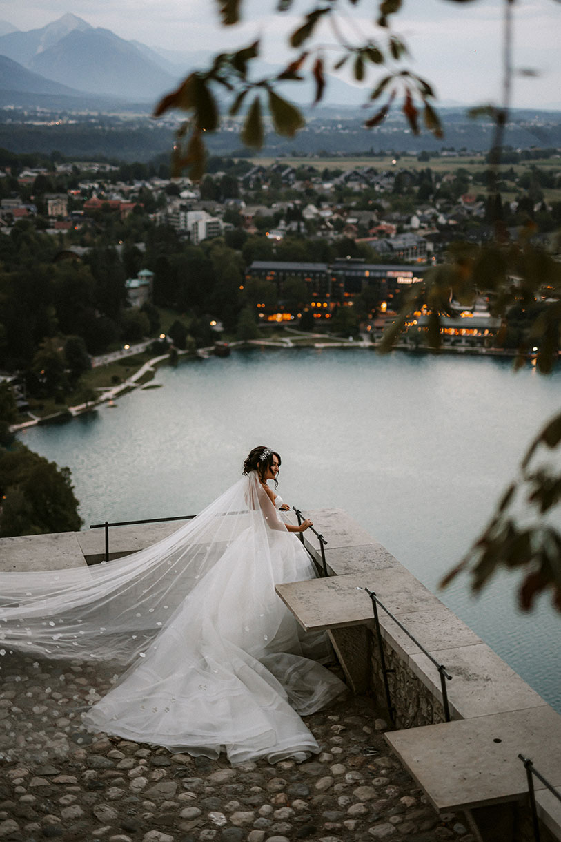 Bride in an amazing snow white princess dress is looking from Bled Castle the Lake Bled Island and Bled town.
