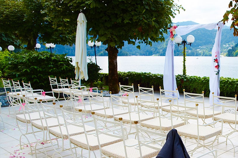 Outdoor setting with woogen arch and white chairs for a civil wedding ceremony at Grand hotel Toplice, Bled.