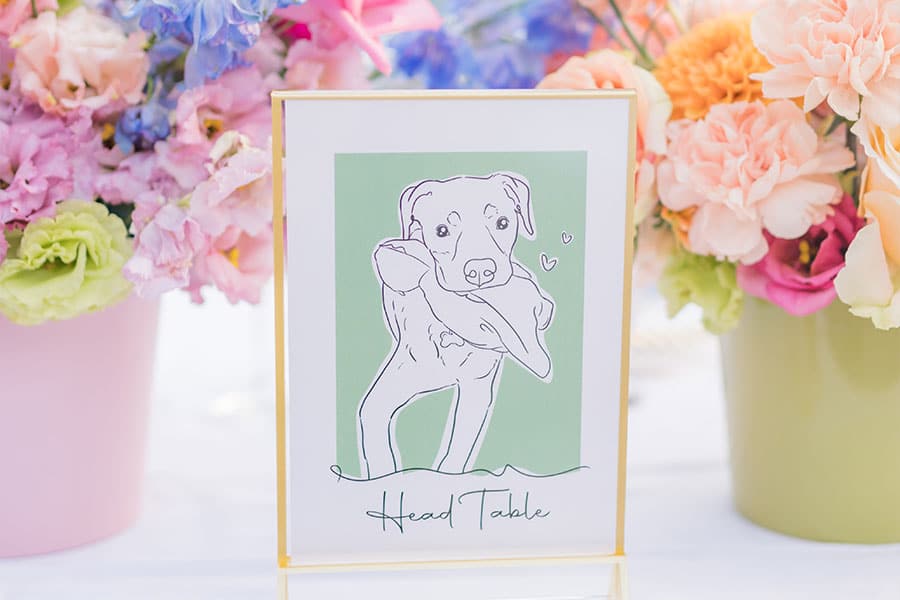 An illustration of a dog on a table number on table number at Lake Bled Castle wedding between vibrant flower decorations.