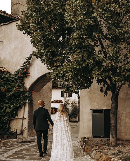 The bride and groom stroll through a quiet village near the best wedding location in Slovenia