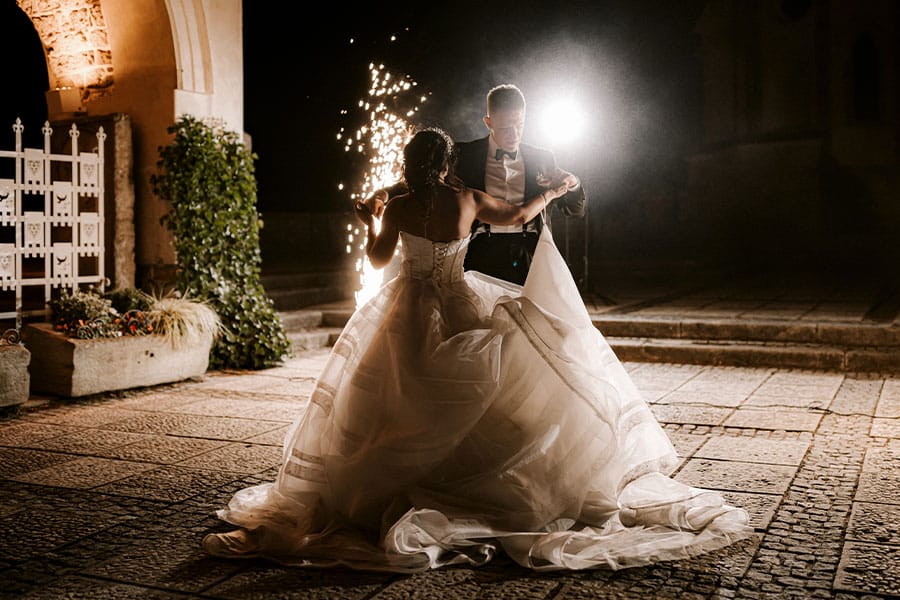 Bride and groom dancing between floor sparkles on the Bled Castle terrace in the night.