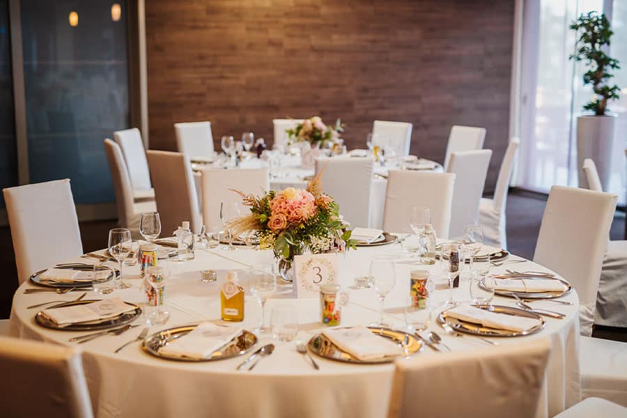 Wedding table setting with cream table cloth, pastel flowers, silver plates and cutlery and table number in Astoria Hotel in Bled.
