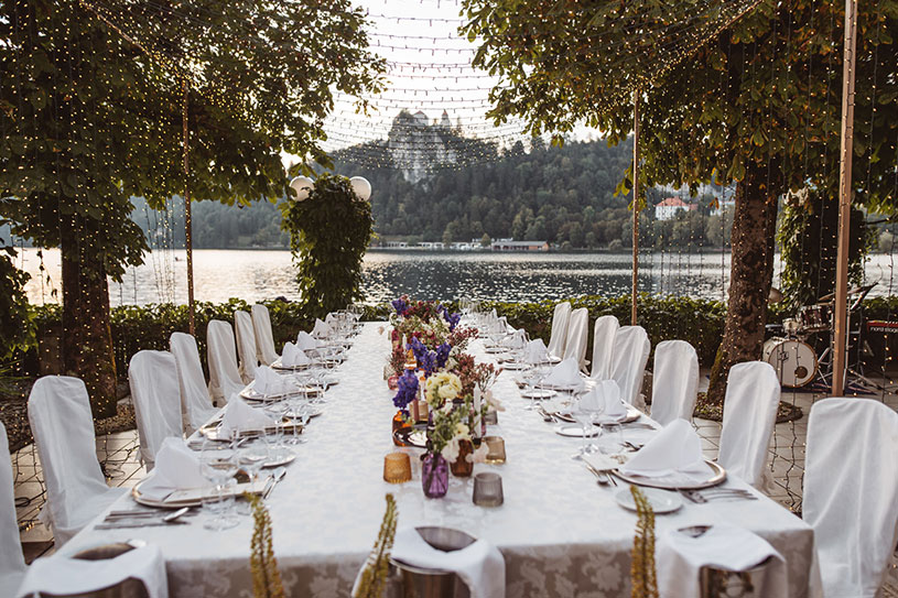 Lake Bled destination wedding dinner setup with long table by the lake