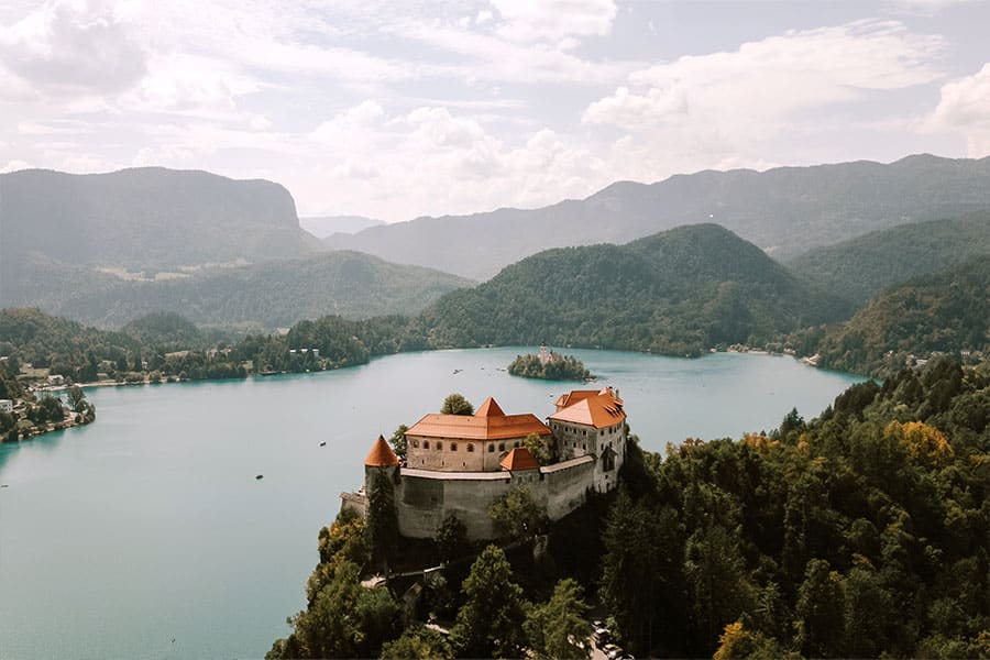 Dramatic aerial view of Bled Castle perched above Lake Bled, one of Slovenia’s most prestigious wedding venues.
