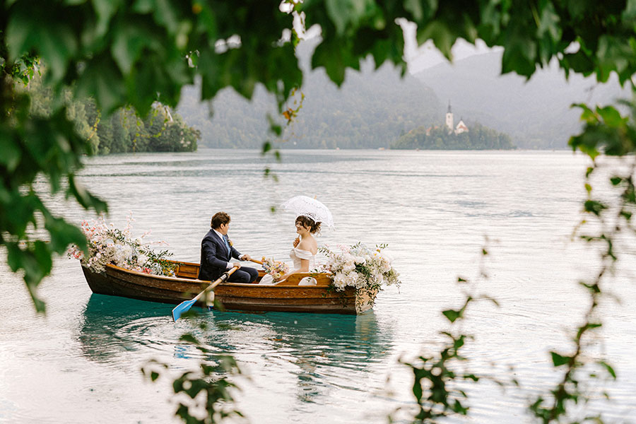 Bride and groom enjoying a romantic traditional boat ride on Lake Bled during their destination wedding