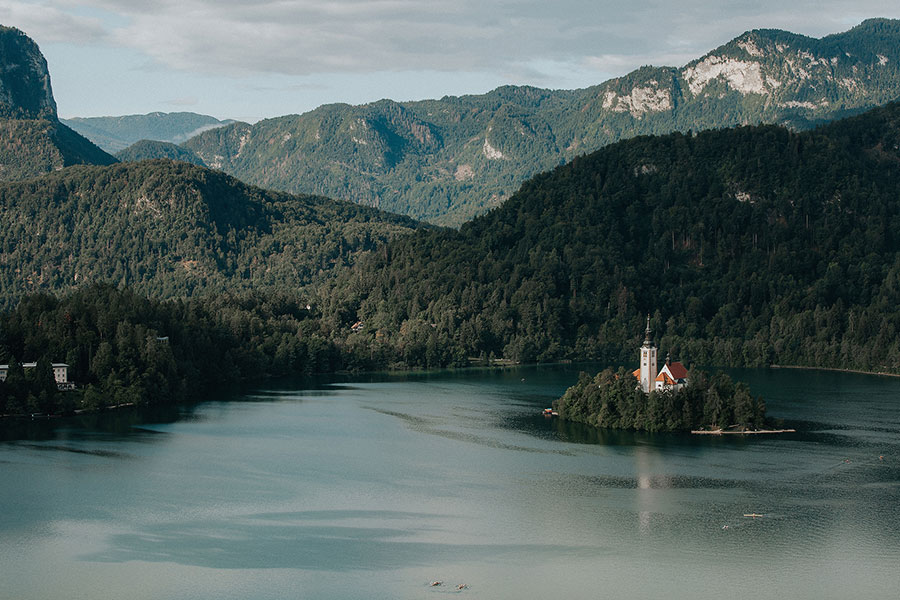 Aerial view of Lake Bled and Bled Island surrounded by mountains, showcasing the natural beauty of a Lake Bled wedding 10–15 K€ in 2026.