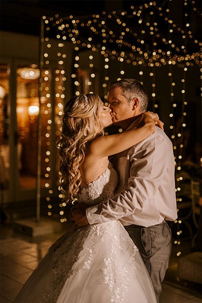 Newlywed are kissing and hugging while dancing in front of a fairy lights at Grand hotel Toplice, Lake Bled.