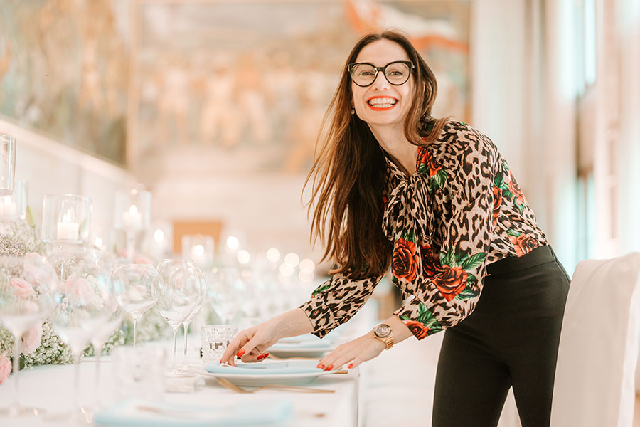 Petra Starbek, luxury wedding planner in Slovenia, styling a wedding table with a warm smile and elegant attention to detail.