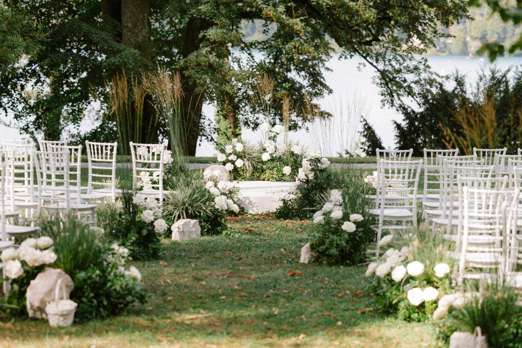 Secluded garden wedding ceremony at Vila Bled with white flowers and chairs, organised by Petra Starbek.