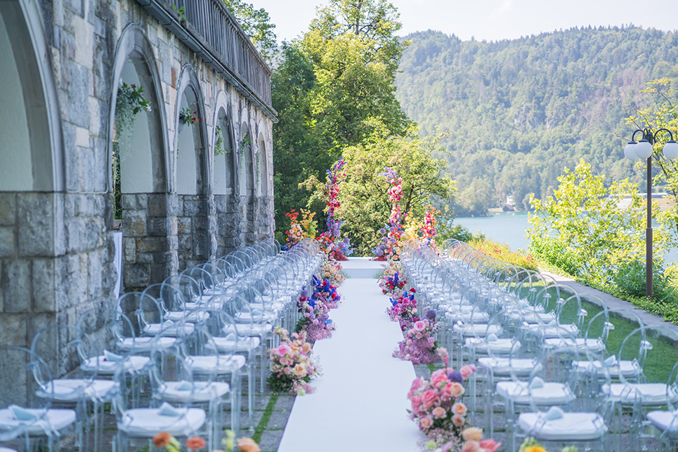 The wedding at lake Bled can be tailored to your wishes as this ceremony was. They wanted vibrant flowers, a unique arch, clear chairs, and a white stage for an intimate wedding in Vila Bled by the lake.
