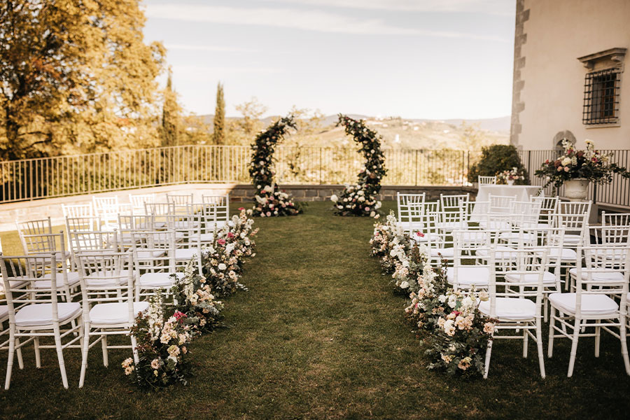 Intimate setting for a small wedding ceremony at villa Vipolže with a flower half-circle arch and white chairs.